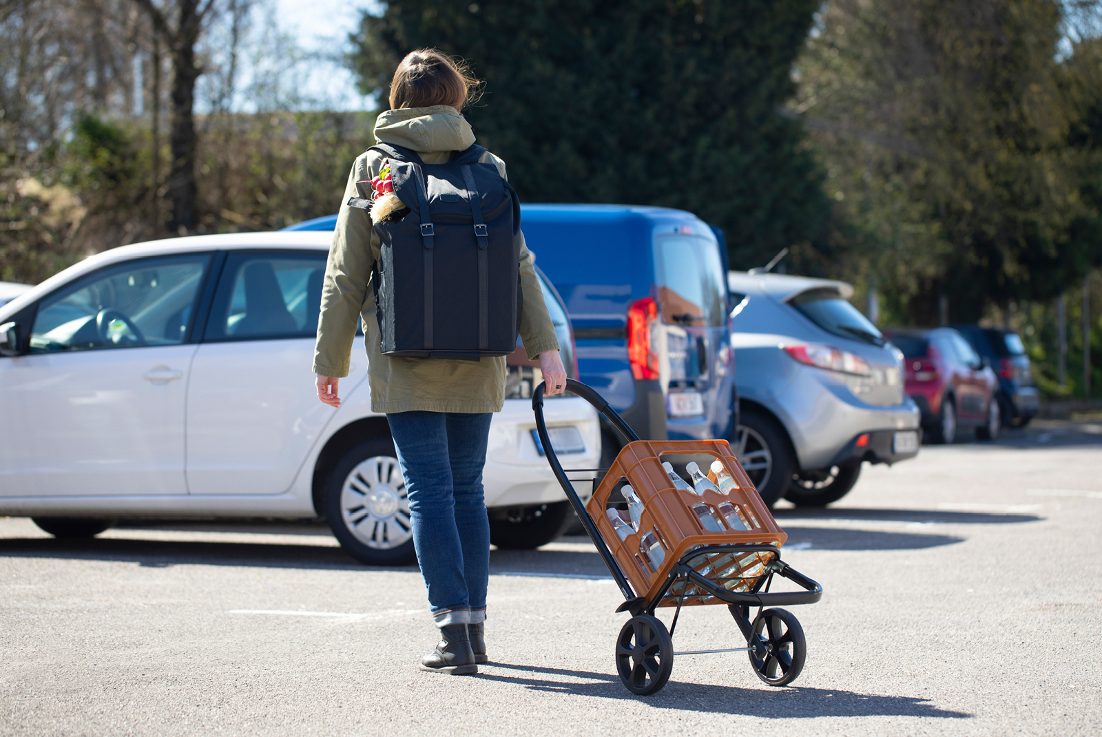 Woman pulling a shopping trolley frame with water box Woman pulling a shopping trolley frame with water box